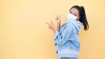 Portrait happy young girl wear mask and jacket jean on orange background. photo