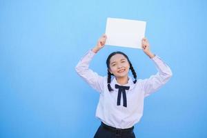 School girl holding billboard on blue background. photo