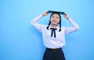School girl holding tablet on blue background. photo