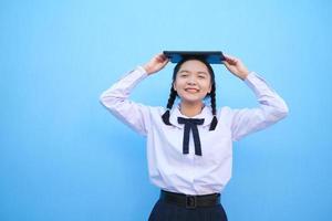 School girl holding tablet on blue background. photo