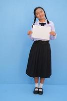 niña de la escuela con cartelera sobre fondo azul. foto
