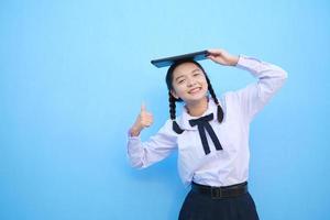 School girl holding tablet on blue background. photo