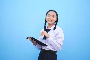 School girl holding tablet on blue background. photo