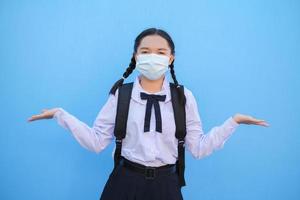 School girl wear mask on blue background,Back to school. photo