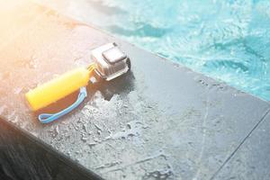 Action camera in water proof case and floating hand grip on pool side photo