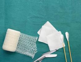 medical tools include scissors, swabs,net roll gauze and blood gauze on green surgical dress  for clean wound