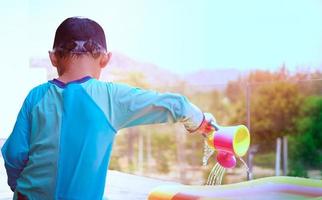 boy plays water pouring on poolside in swimming pool with sun light in summer vacation time photo