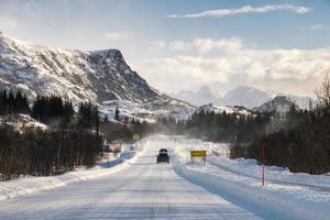 Car driving on snowy road with mountain range photo