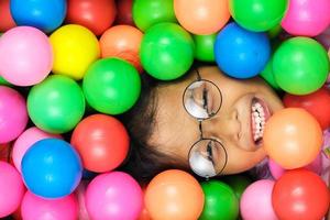 Portrait of a little girl smiling broadly with colorful plastic balls around her photo