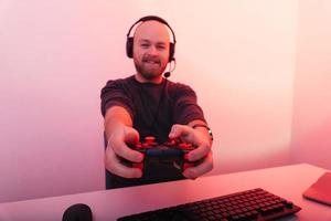 un hombre alegre que usa auriculares está jugando con su joystick en la computadora. foto