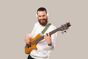 Photo of young handsome bearded man playing at bass guitar with 5 strings
