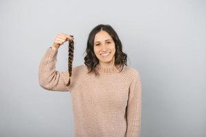 alegre retrato de una joven sosteniendo una trenza de cabello para donar.