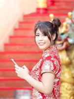 hermosa chica asiática vestida con traje nacional chino que busca usar datos de teléfonos inteligentes foto