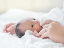 A beautiful Asian woman holds her newborn baby with love and cherish and feeds photo