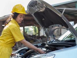 The woman in the mechanic's work set is using a wrench to open the parts of the engine photo