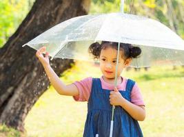 una niña estaba felizmente parada en un paraguas contra la lluvia foto