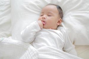 A newly born bastard is wrapped in a white cloth and sleeps on a bed photo