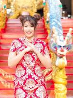 A beautiful Asian girl in a Chinese national costume raises his hands to bow photo
