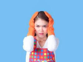 A beautiful Asian woman holds her hand in the head with stress and fatigue in cleaning the house photo