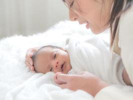 A beautiful Asian woman is looking at her newborn baby with happiness and love photo