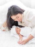 A beautiful Asian woman is happily hugging her newborn baby and loving her photo