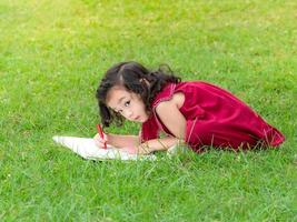 The girl sitting on the grass, drawing with colored pencils Is learning outside of school photo