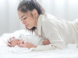 A beautiful Asian woman is looking at her newborn baby with happiness and love