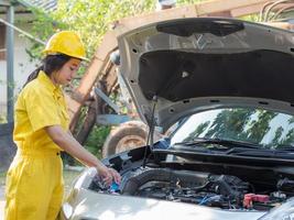 la mujer en el técnico de ropa de trabajo está abriendo la tapa del tanque del motor y rellenando el nivel del agua foto