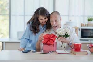 An elderly European couple and an Asian woman happily give each other gift boxes and flowers on the occasion of Valentine's Day photo