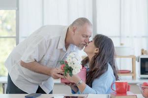 An elderly European couple and an Asian woman happily give each other gift boxes and flowers on the occasion of Valentine's Day photo