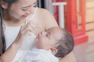 una hermosa mujer asiática sostiene a su hija recién nacida que duerme amorosamente y aprecia y cría felizmente foto