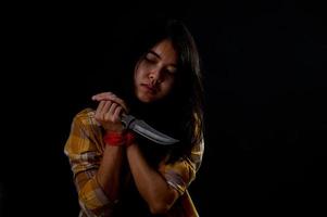 A teenage girl is bound by a rope, stresses and tries to use a knife photo