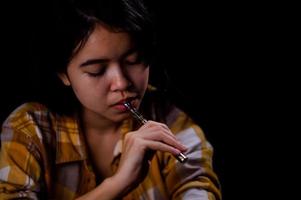 Teenage girl vaporize cannabis through a vaporizer containing cannabis oil in a tube after electrical heating photo