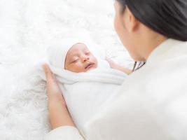 una hermosa mujer asiática está mirando a su bebé recién nacido con felicidad y amor foto