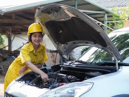 la mujer en el trabajo del mecánico está usando una llave para abrir las partes del motor foto