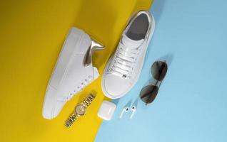 women's white sneakers with accessories on yellow and light blue background photo