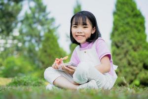 Image of Asian little girl studying at park photo