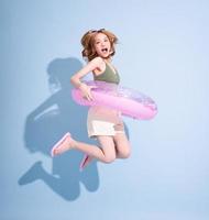 Image of young Asian girl holding swimming float on blue background, summer vacation concept photo