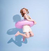 Image of young Asian girl holding swimming float on blue background, summer vacation concept photo