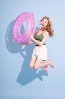 Image of young Asian girl holding swimming float on blue background, summer vacation concept photo