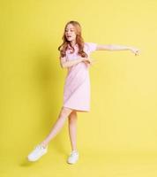 Full length image of young Asian girl standing on yellow background photo