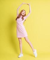 Full length image of young Asian girl standing on yellow background photo