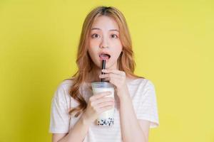 Image of young Asian girl drinking milk tea on yellow background photo