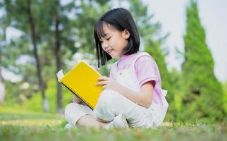 Image of Asian little girl studying at park photo