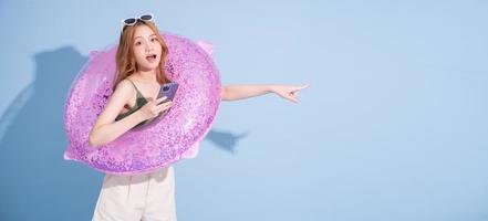 Image of young Asian girl holding swimming float on blue background, summer vacation concept photo