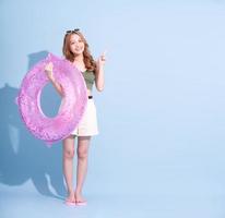 Image of young Asian girl holding swimming float on blue background, summer vacation concept photo