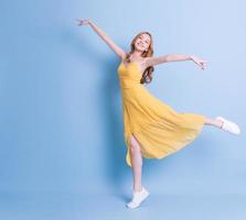 Full length image of young Asian woman wearing yellow dress on blue background photo