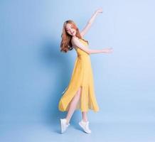 Full length image of young Asian woman wearing yellow dress on blue background photo