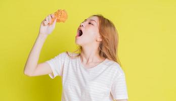 Image of young Asian girl eating chicken fried on yellow background photo