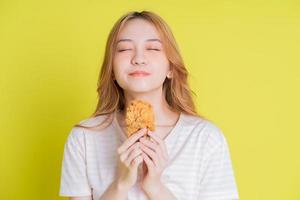 Image of young Asian girl eating chicken fried on yellow background photo